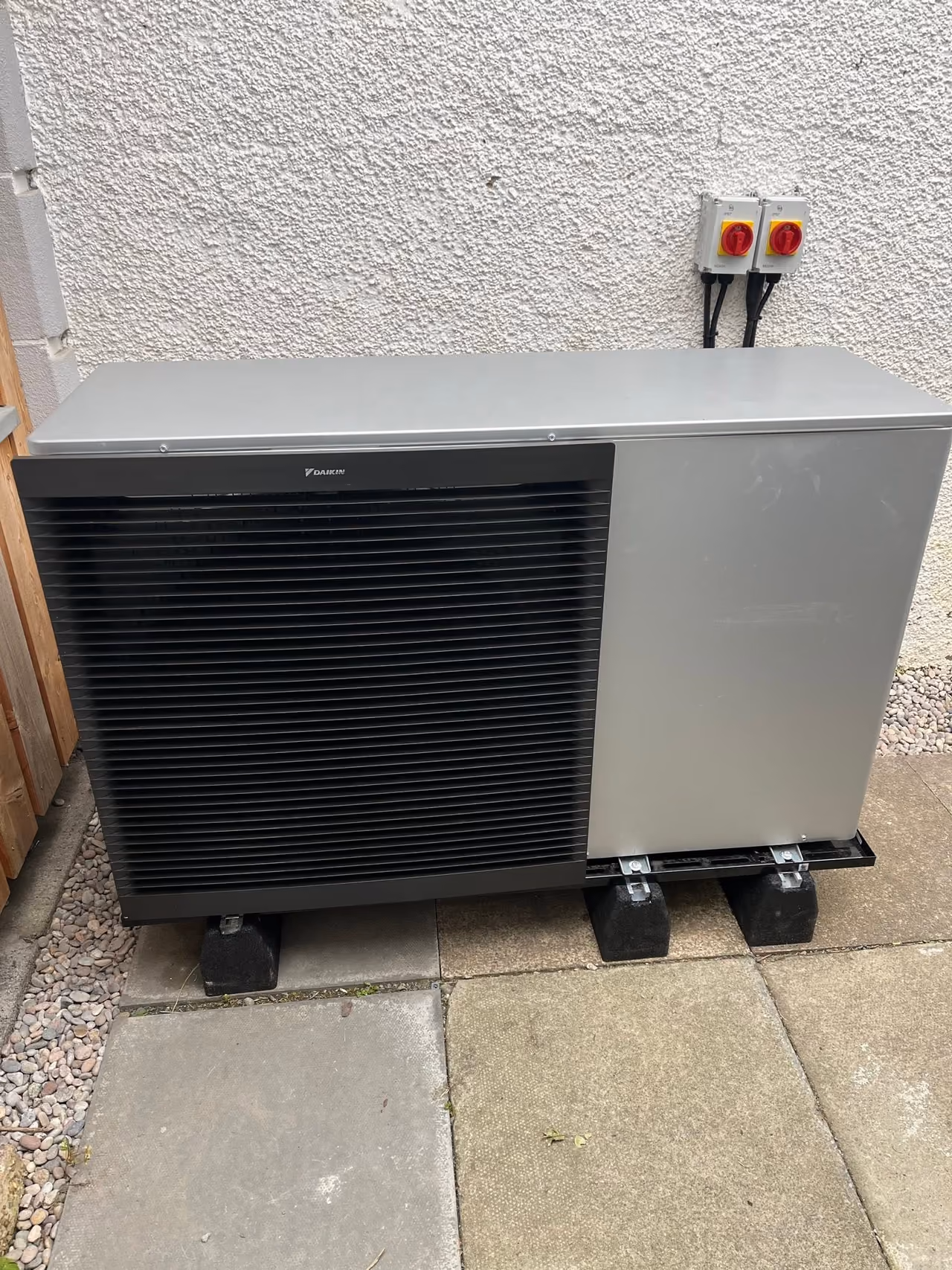 Daikin air source heat pump installed beside a rendered wall