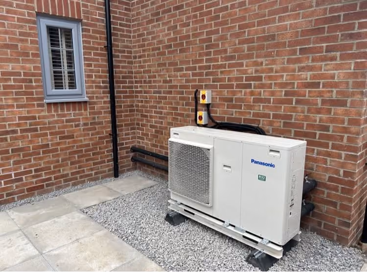 Panasonic air source heat pump installed beside a brick home